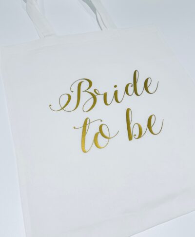 Close up of a white tote bag or gift bag featuring the phrase 