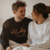Lifestyle image of a husband and wife in matching 'Hubby Wifey' sweatshirts after their wedding. Perfect for personalised couple hoodies, wedding gifts, anniversary presents, and newlywed apparel