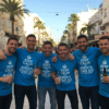 Custom stag do t-shirts blue matching group photo in Benidorm. Group of men wearing matching blue stag party tops drinking beer. Stag do tops with 'Keep Calm and It's Andy's Stag Do' slogan.