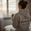 Personalised 'Mrs.' wedding hoodie worn by a bride to be, displaying her new name and wedding date on the back. Ideal custom apparel for bridal showers, hen dos, and newlywed gifts.