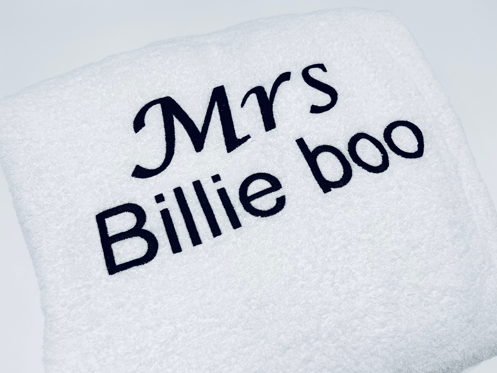 White terry towelling robe with custom black embroidery showing 'Mrs' in script above 'Billie boo' in a bold font. Ideal personalised gift for a bride or wife.
