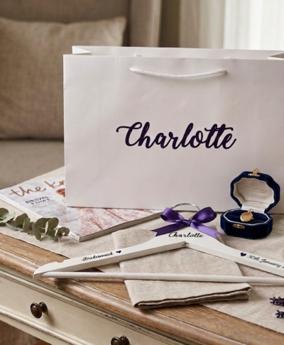 A personalised wooden bridesmaid hanger and gift box set on an elegant white table, featuring a custom name 
